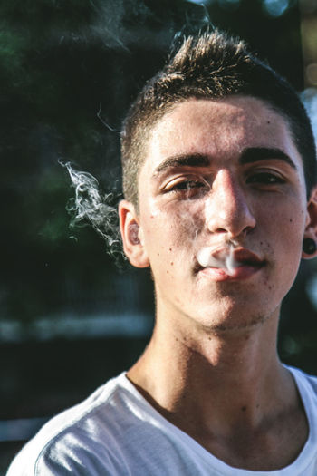 Close-up portrait of young man smoking outdoors