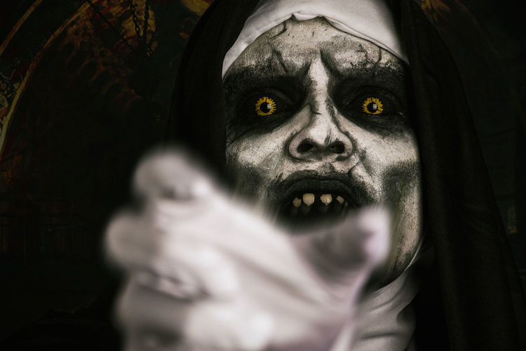 Close-up portrait of woman in demon nun costume gesturing at night