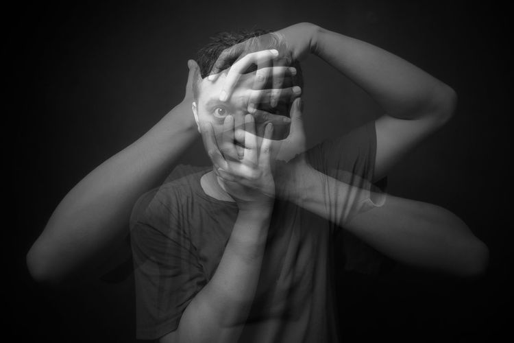Midsection of man covering face against black background