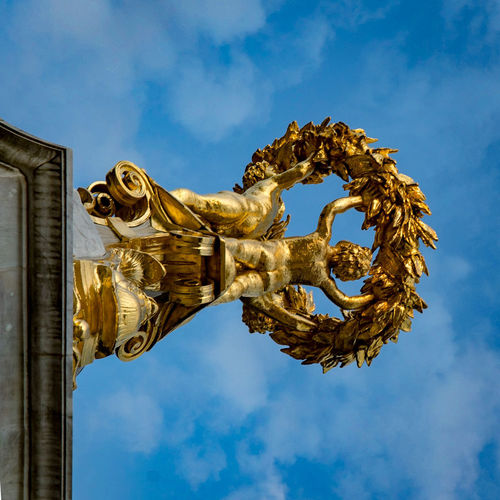 Low angle view of golden statue against sky