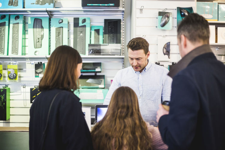Salesman showing computer equipment to customers in electronics store