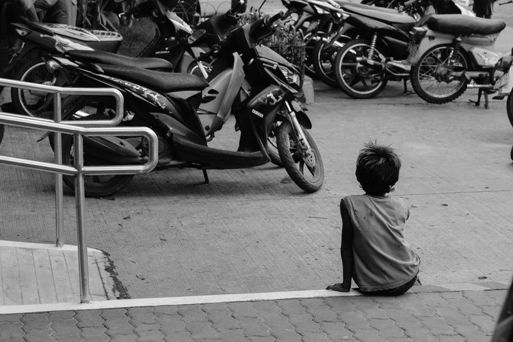 Rear view of boy sitting at parking lot