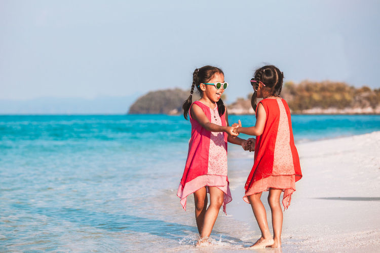 Girls playing while standing at beach