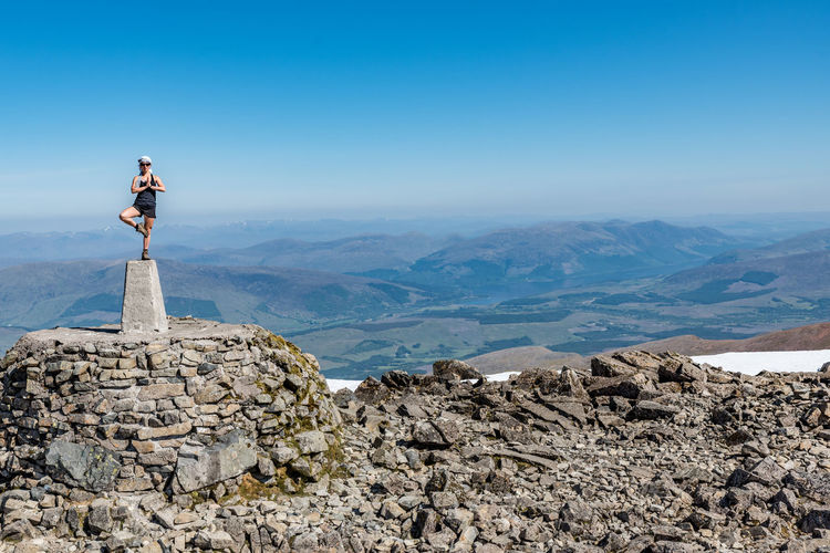 Man standing on rock against sky
