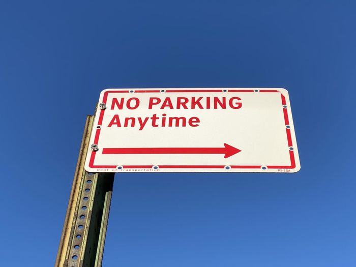 Low angle view of no parking anytime road sign against clear blue sky in mount vernon new york 