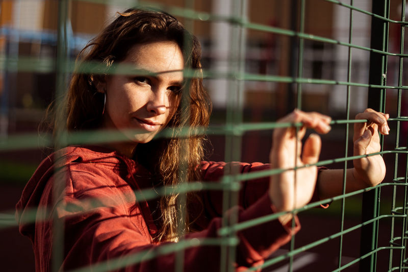 Portrait of young woman seen through fence