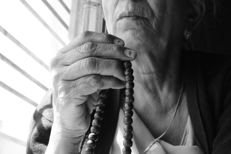 Midsection of senior woman holding bead necklace