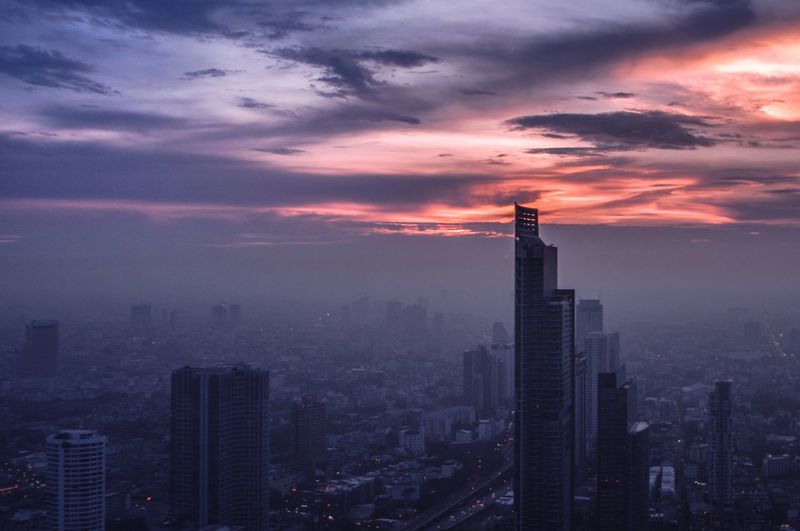 Cityscape against cloudy sky at sunset