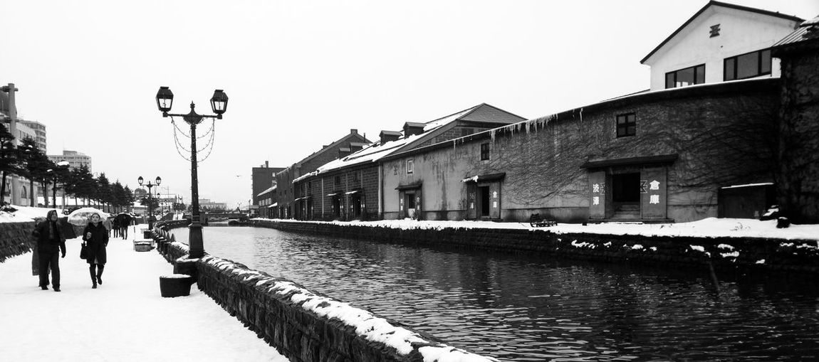 Buildings by canal during winter