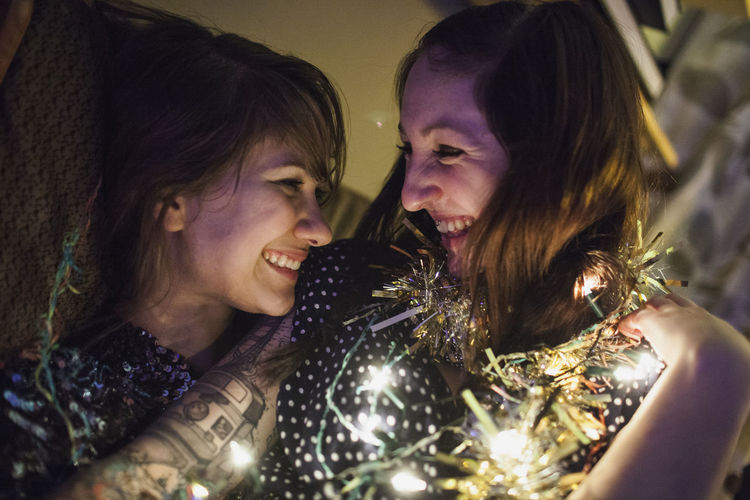 Two friends wrapped in tinsel and fairy lights