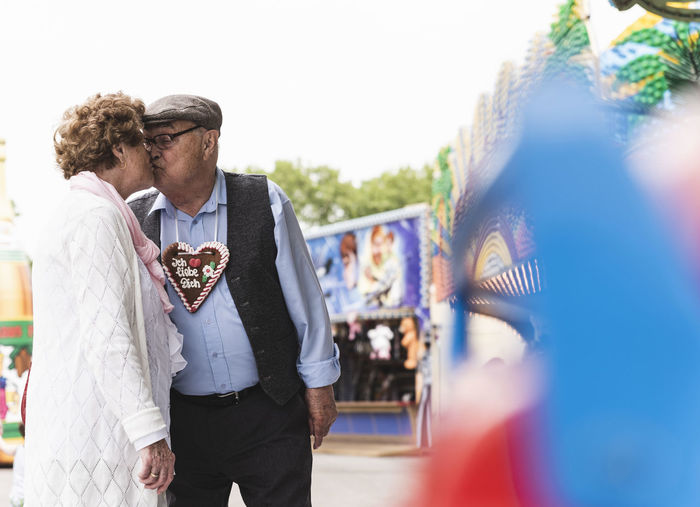 Senior couple with gingerbread heart kissing on fair
