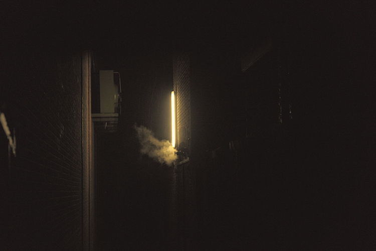 Smoke emitting from illuminated building against sky at night