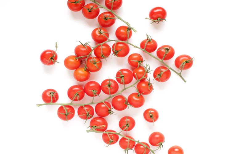 High angle view of red berries over white background