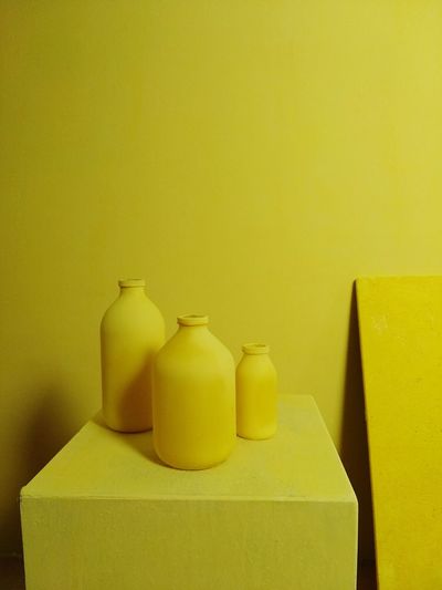 Close-up of yellow bottles on shelf against wall