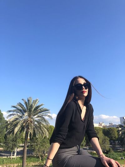 Young woman in sunglasses against clear blue sky