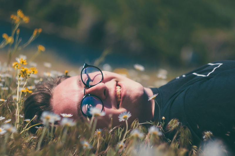  young man wearing eyeglasses while lying on meadow
