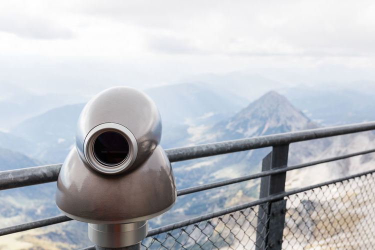 Coin-operated binoculars on mountain against sky