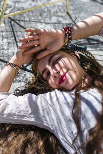 Close-up of smiling hipster young woman lying on concrete floor