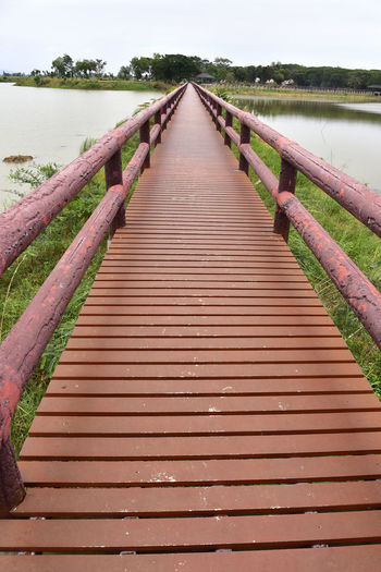 Wooden bridge over water against sky