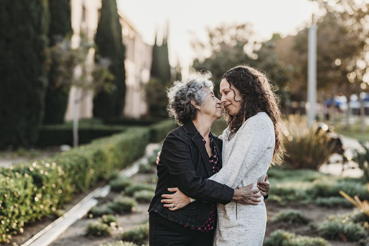 Active senior woman and adult daughter hugging each other outside