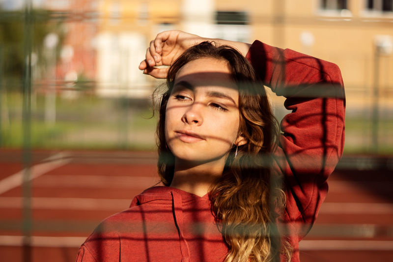 Young woman looking away seen through fence