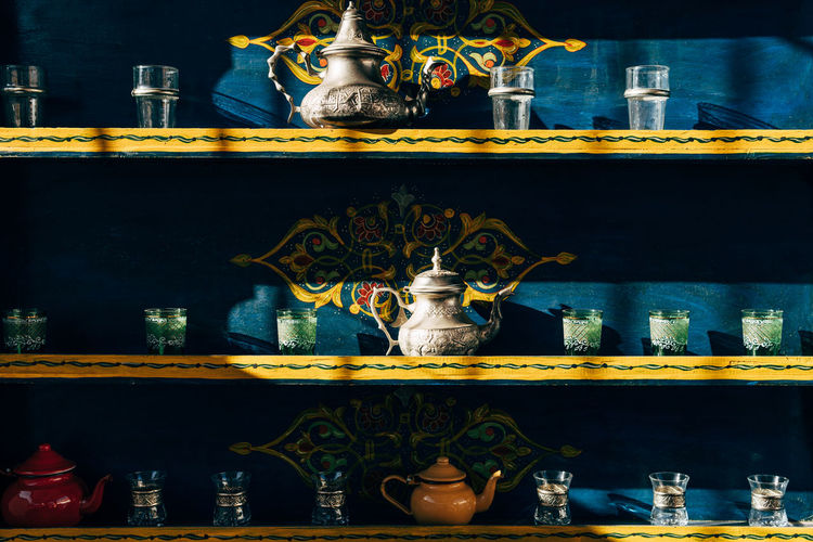 Ceramic and metal kettles with glasses small cups on colorful shelves in morocco