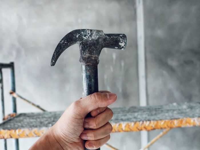 Close-up of hand holding hammer at construction site