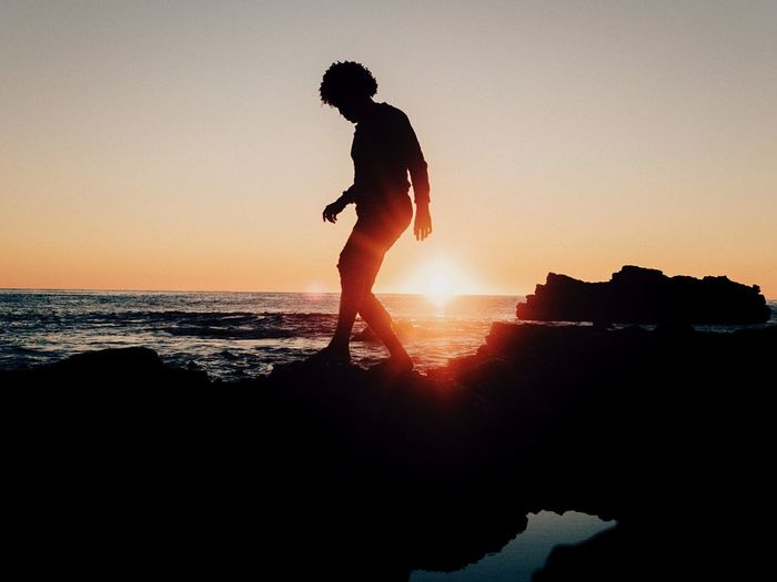 Silhouette people on beach against clear sky during sunset