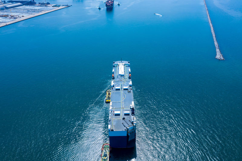Aerial view ro-ro ship loading new cars. automotive container carriers sailing on the sea export 
