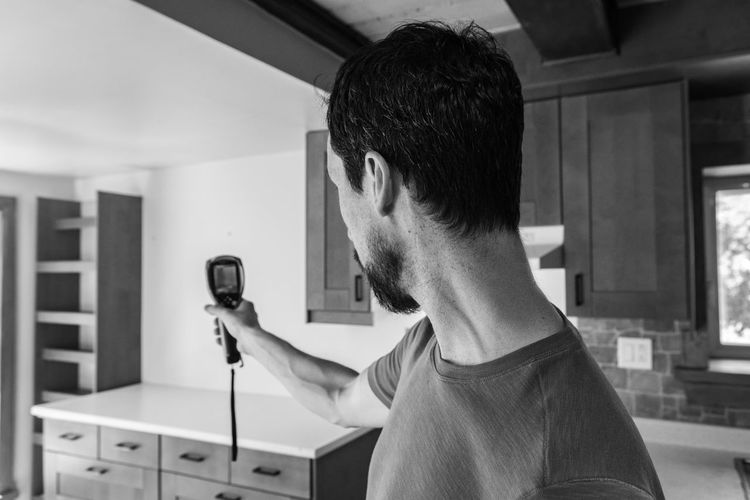 Portrait of young man holding camera at home