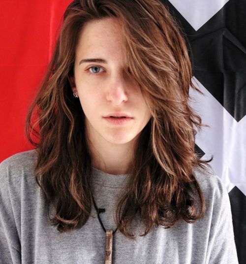 Portrait of beautiful young woman standing against curtains