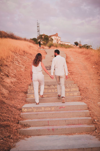 Rear view full length of young couple moving up on steps