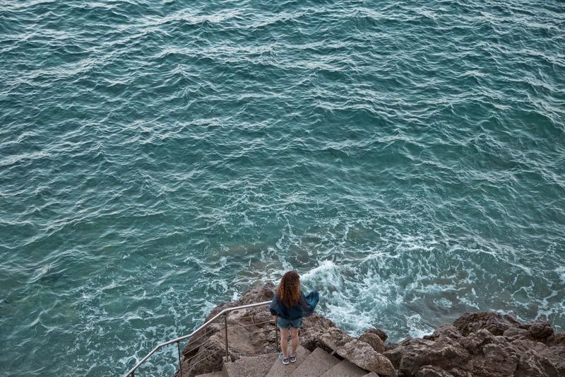 High angle view of woman standing on steps by sea