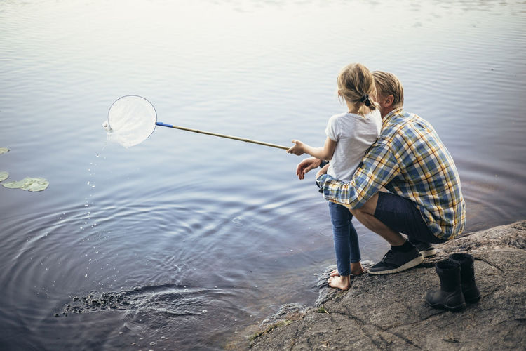 High angle view of father and daughter fishing in lake