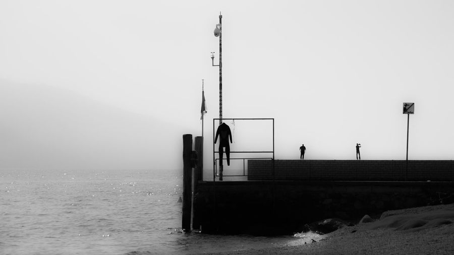 Silhouette man standing on sea against sky