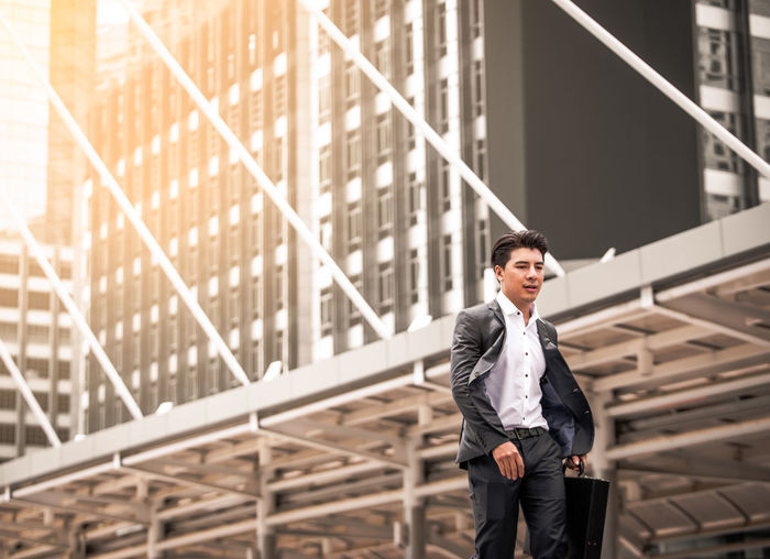 Young businessman walking against building in city