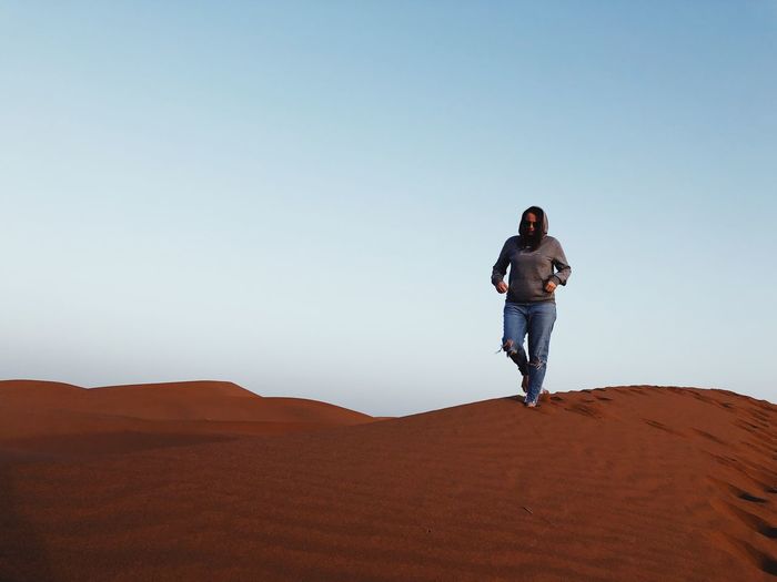 Full length of man standing on desert against clear sky