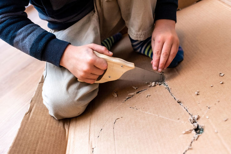 Low section of boy cutting cardboard