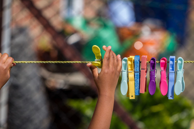 Close-up of hand touching clothespins hanging on clothesline
