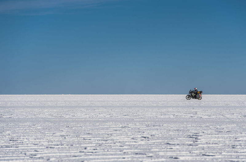 Man riding his touring motorbike on the salt flats of uyuni in bolivia