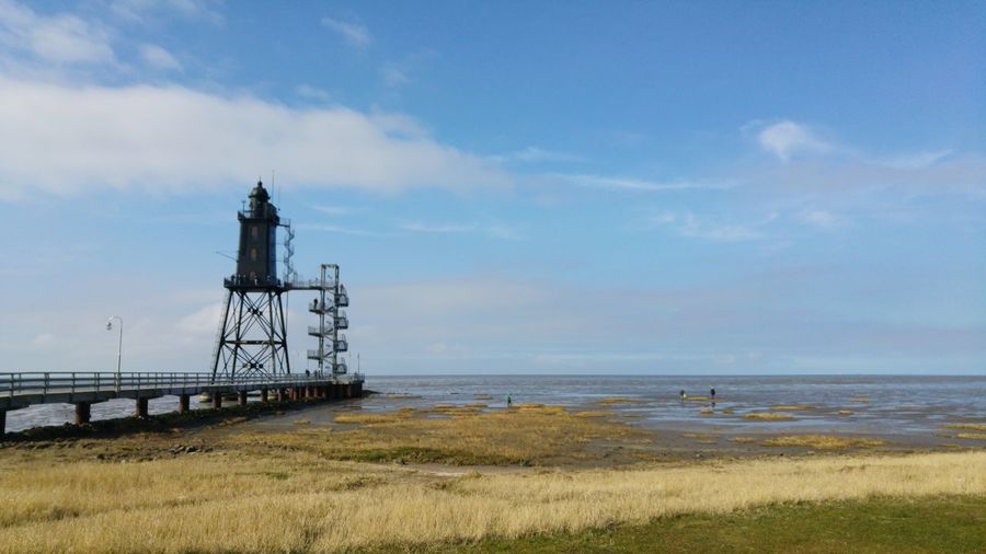 Lighthouse by sea against sky