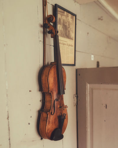 Close-up of old violin hanging against white wall