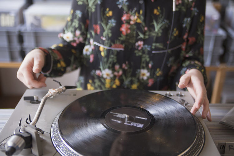 Hands of young woman using record player