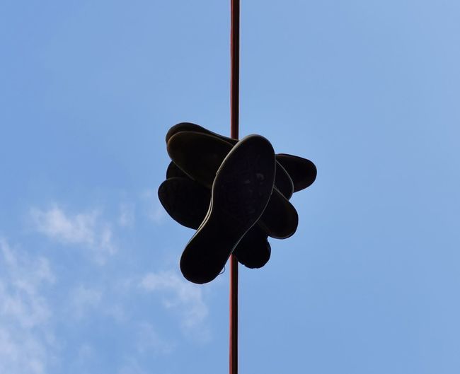Low angle view of shoes on street against sky