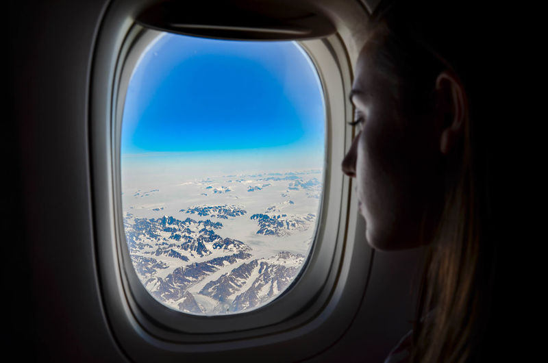 Close-up of woman looking through airplane window