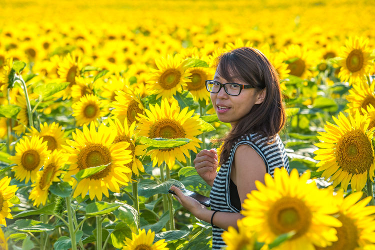 Portrait of smiling woman amidst sunflowers