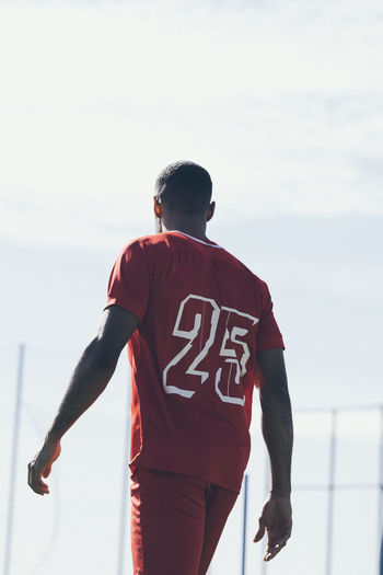 Back view of african american soccer player walking on grass pitch