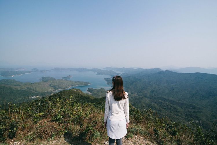 Rear view of woman standing on mountain against sky