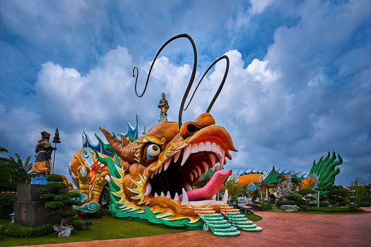 Low angle view of dragon statue against cloudy sky
