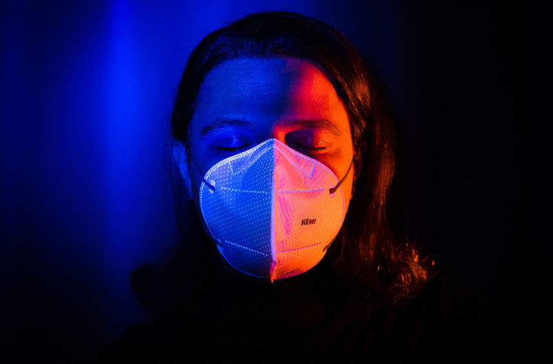 Close-up of woman wearing mask against black background